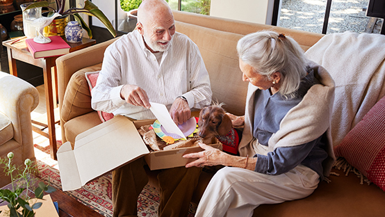 senior couple unpacking parcel with its dog