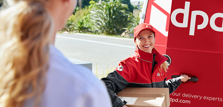 DPD driver (woman) hands over parcel to a consignee in front of the dpd van