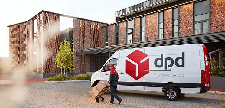 DPD Fahrer mit Sackkarre und Transporter vor einem Gebäude