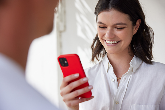 Frau schaut auf ihr Smartphone und lächelt