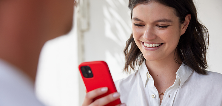 Frau schaut auf ihr Smartphone und lächelt