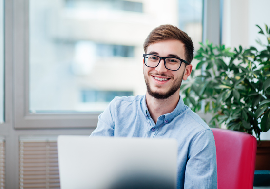 Lehrling - IT Systemtechniker - Junger Mann mit Brille vor Laptop