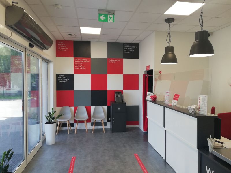 Wnętrze punktu DPD: recepcja, krzesła dla klientów i dekoracyjna ściana.