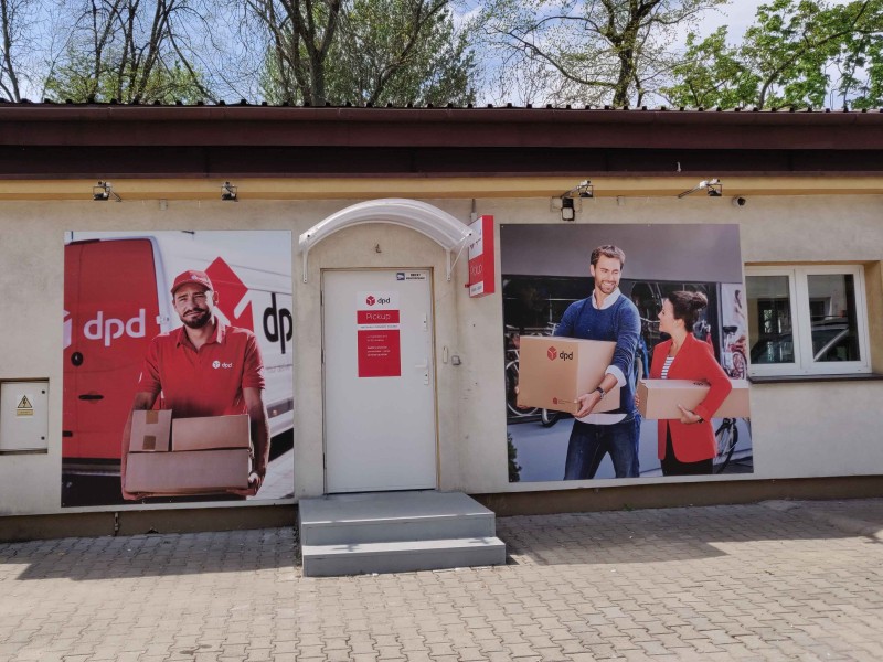 Punkt DPD Pickup: wejście z plakatem kuriera i pary z paczkami.