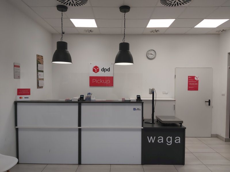 Punkt DPD Pickup: biała lada z logo, waga paczek, wnętrze lokalu.