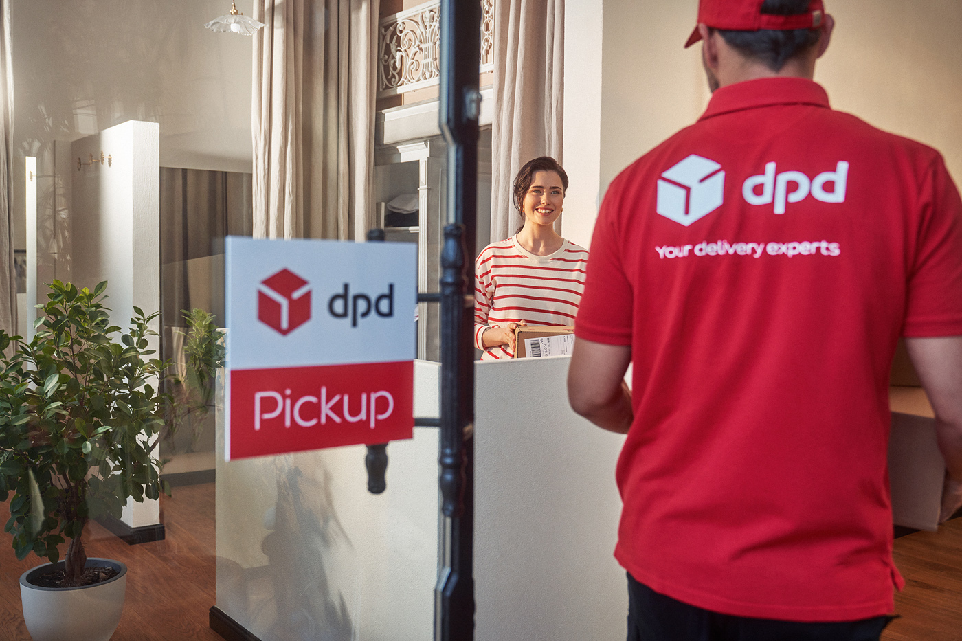 Kurier DPD odbiera paczkę od klientki w punkcie odbioru. Znak "Pickup".