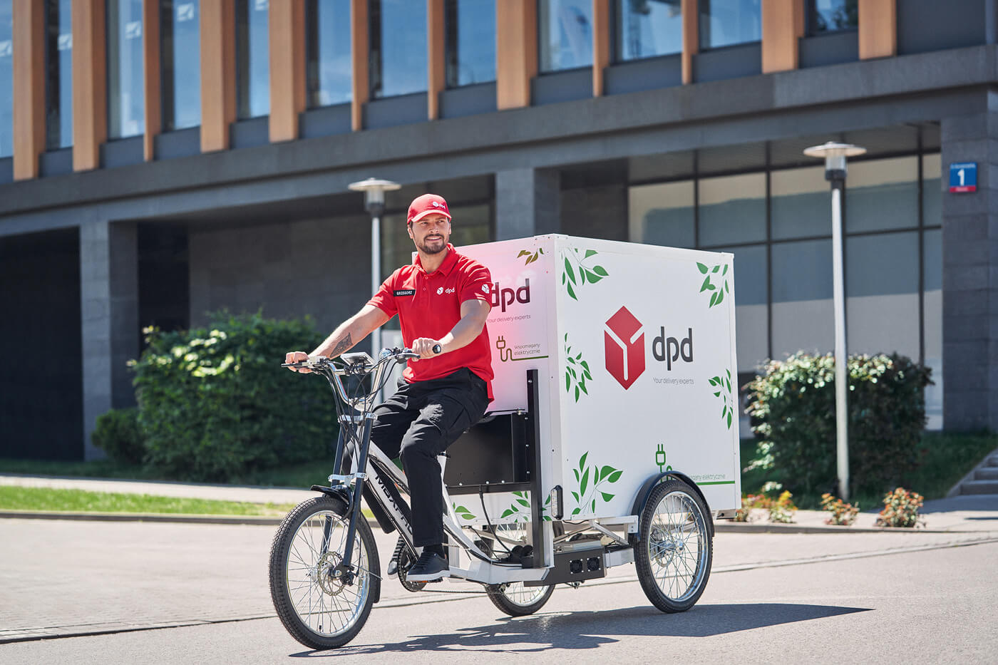 Kurier DPD na rowerze cargo z logo firmy dostarcza przesyłki.