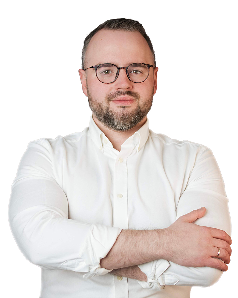 Portret mężczyzny w okularach i białej koszuli z założonymi rękami.