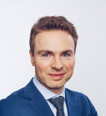 Portret mężczyzny w niebieskiej marynarce i krawacie w kropki.