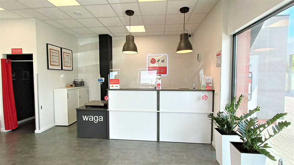 Wnętrze punktu DPD Pickup z ladą obsługi klienta i wagą do paczek.