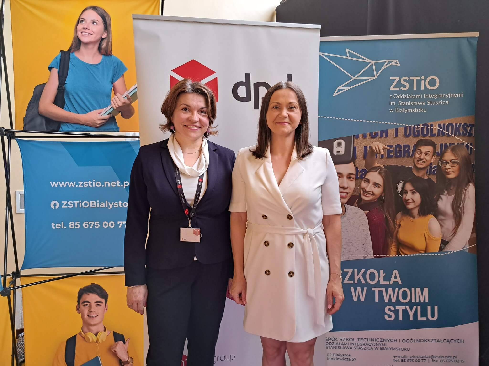 Dwie kobiety na tle banerów DPD i ZSTiO w Białymstoku. Współpraca edukacyjna.