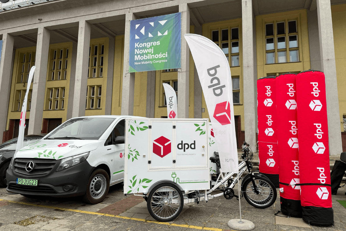 Pojazdy DPD: furgonetka i rower cargo z napędem elektrycznym na tle budynku.