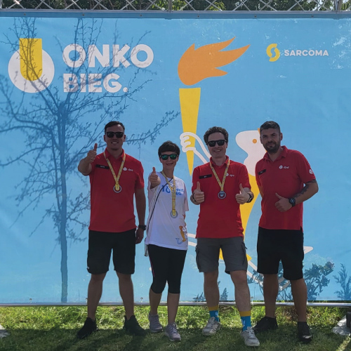 Drużyna DPD na tle baneru Onko-Bieg Sarcoma z medalami.