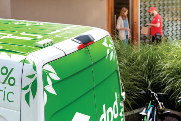Kurier DPD doręcza paczkę z elektrycznego samochodu.