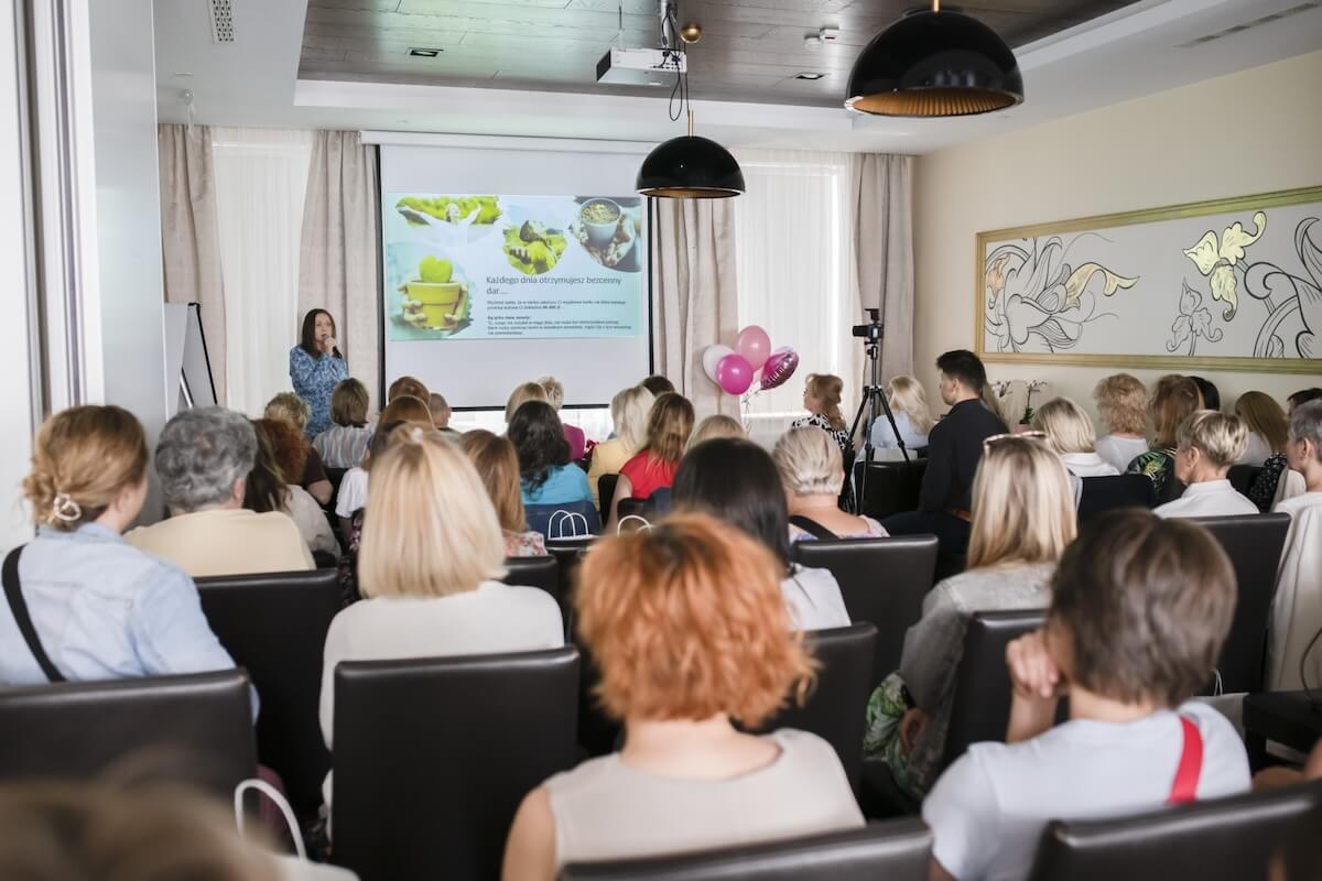 Prezentacja dla grupy osób w sali konferencyjnej, rzutnik z grafiką.