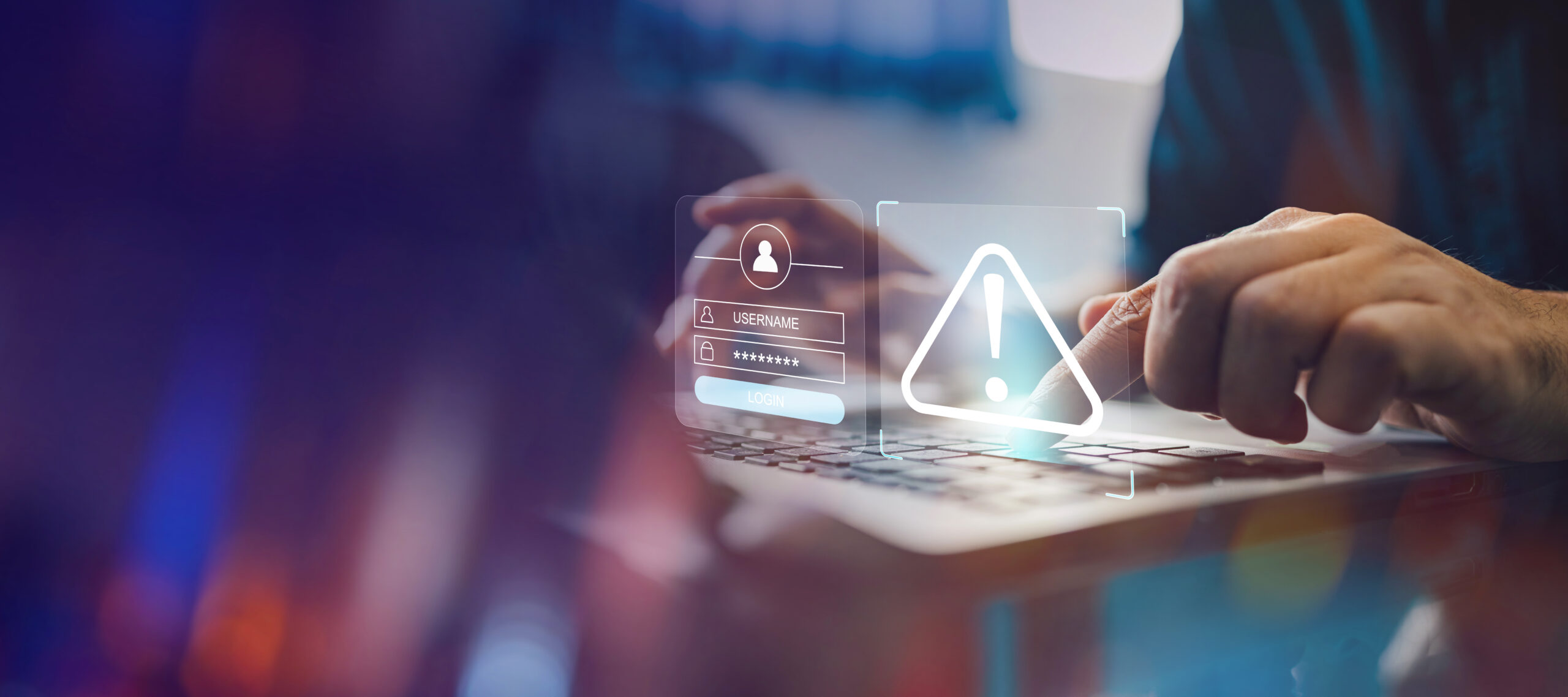 poradnik_phishing_1 Ręce na klawiaturze laptopa z wyświetlanym ostrzeżeniem o zagrożeniu: Osoba korzystająca z laptopa, z ikonami ostrzegawczymi na ekranie, symbolizującymi phishing.