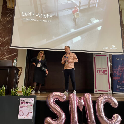 Dwóch prelegentów z DPD Polska na scenie podczas XIV Studenckiej Konferencji Morskiej, z prezentacją na ekranie w tle.