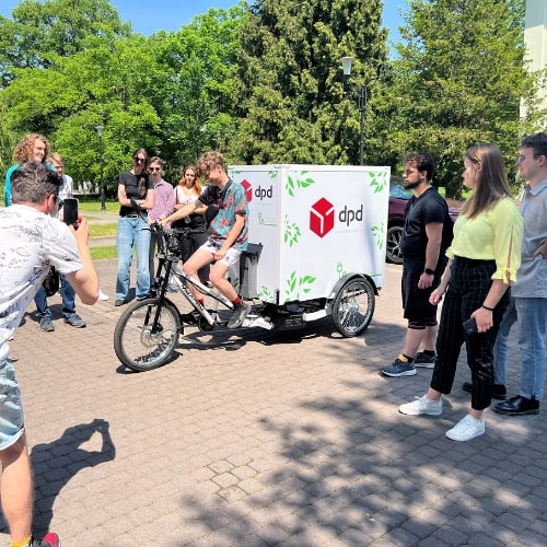 Rower cargo DPD z logo firmy, prezentowany grupie osób.