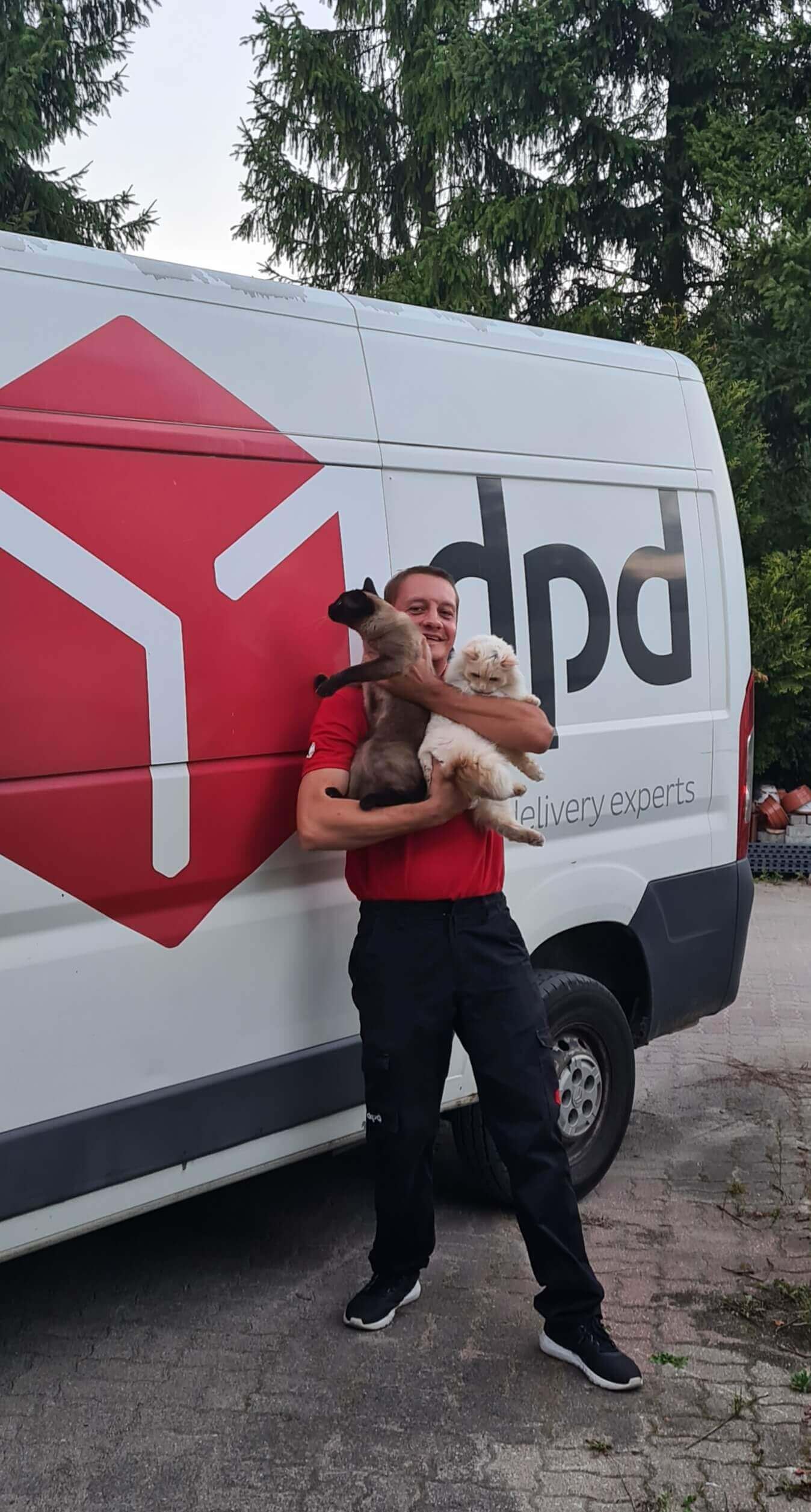 Kurier DPD trzyma dwa koty na tle furgonetki DPD.