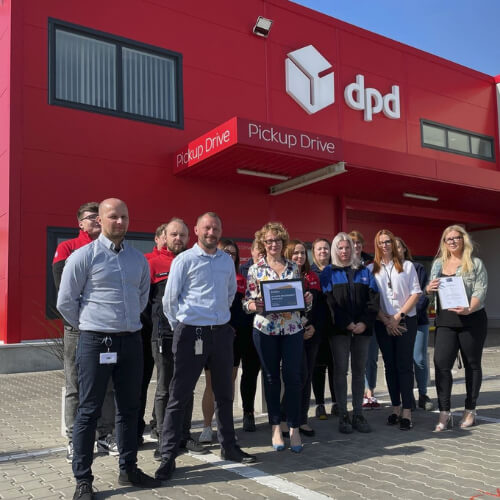 Zespół DPD Polska przed siedzibą firmy, prezentujący wyróżnienie Poland's Best Employers 2024, potwierdzające wysoką pozycję firmy w prestiżowym rankingu Forbes.