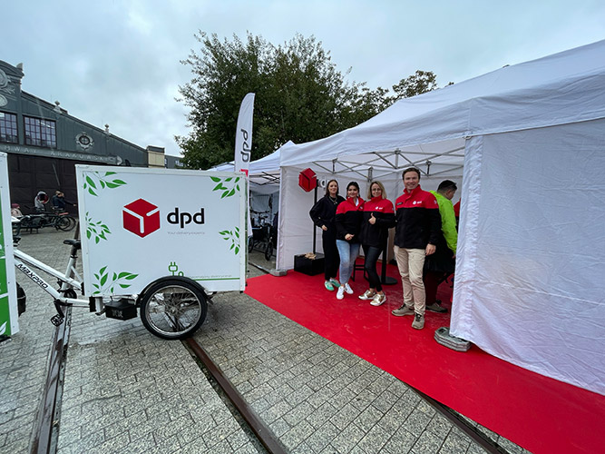 Image-(6) Przedstawiciele DPD Polska w strefie DPD na Cargo Bike Festiwal w Krakowie, stoją obok roweru cargo promującego zrównoważony transport.