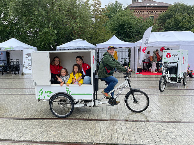 Image-(7) Przedstawiciele DPD Polska przewożą dzieci rowerem cargo podczas Cargo Bike Festiwal w Krakowie, promując zrównoważony transport.