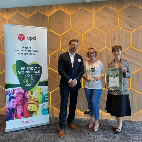 Projekt bez nazwy (65) Trzy osoby z zespołu DPD Polska otrzymują wyróżnienie Friendly Workplace 2024. Na zdjęciu przedstawiciele DPD stoją na tle ściany z motywem heksagonalnym, obok roll-upu z logo DPD i napisem 'Razem tworzymy przyjazne miejsce pracy'.