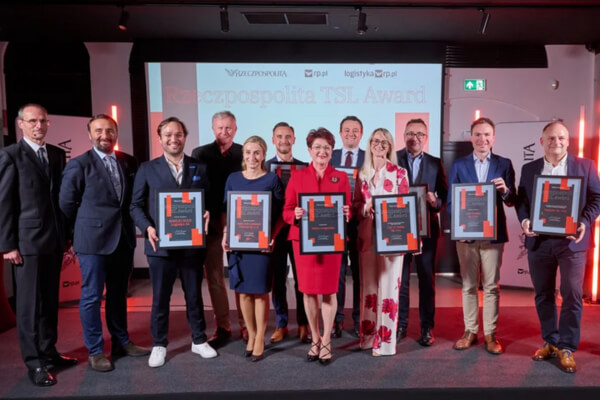 DPD Polska po raz kolejny z nagrodą TSL Award dziennika Rzeczpospolita Laureaci nagrody Rzeczpospolita TSL Award, w tym przedstawiciele DPD Polska, stoją z dyplomami na scenie po ceremonii wręczenia nagród. W tle widnieje ekran z logotypami organizatorów i nazwą wydarzenia.