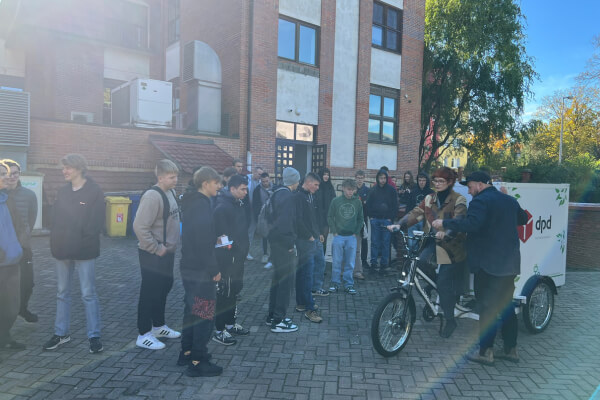 Uczestnicy Dolnośląskiego Festiwalu Nauki obserwują demonstrację roweru cargo DPD, prezentując ekologiczne alternatywy transportu miejskiego.