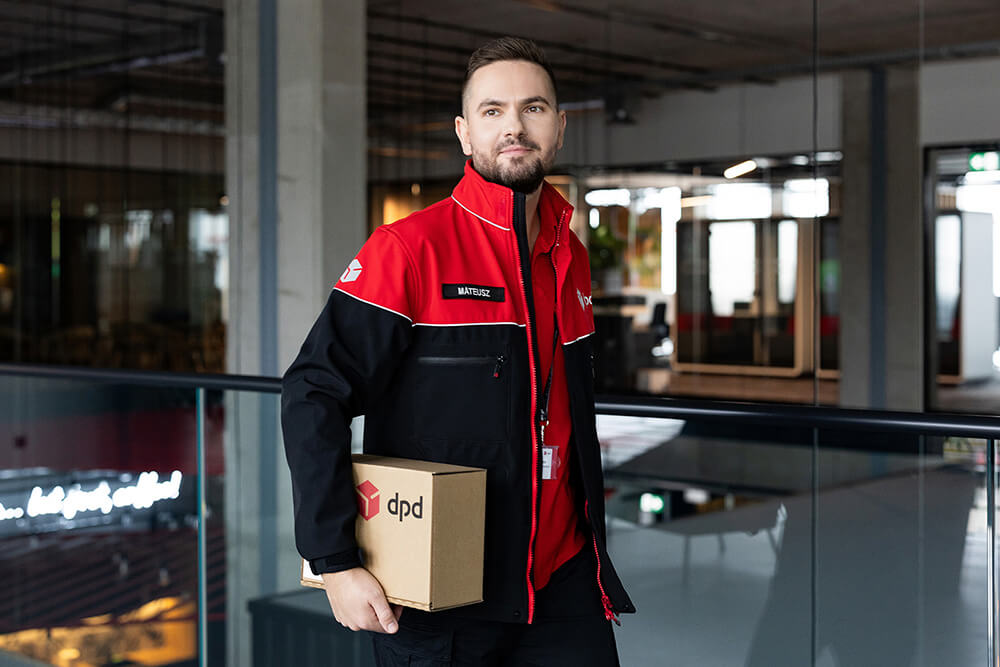 Kurier DPD w uniformie trzyma paczkę. Dostawa przesyłek DPD.