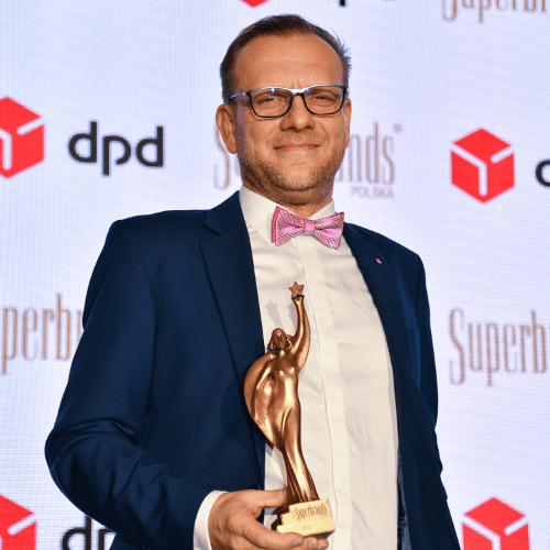 Mężczyzna w garniturze z nagrodą Superbrands na tle logo DPD.