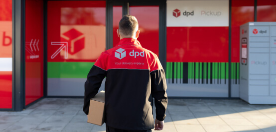 Kurier w kurtce DPD stoi przed wejściem do punktu DPD Pickup