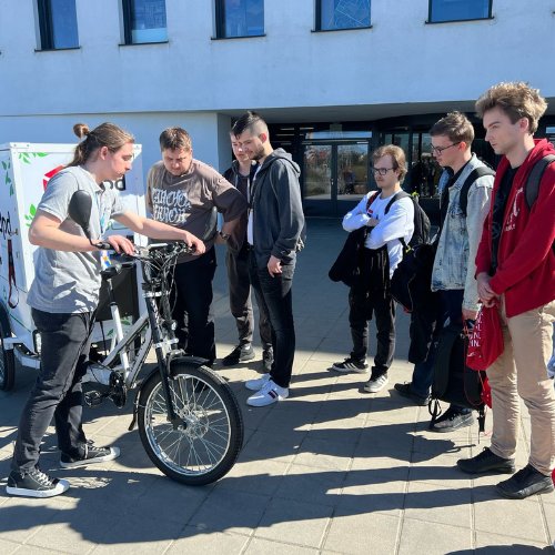Młodzież i studenci oglądający ekologiczny rower cargo DPD Polska, symbol zrównoważonych dostaw.