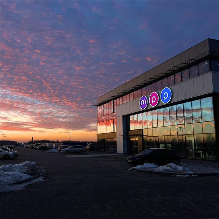 Przeszklona siedziba budynku z literami w kółko m, p, p w tle zachód słońca