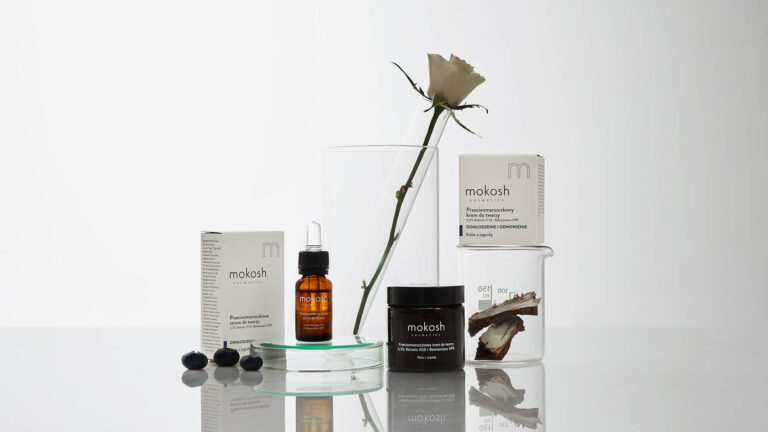 Kosmetyki Mokosh na białym tle, biała róża w wazonie
