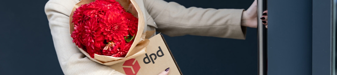 Pracownik DPD podaje klientowi paczkę przy stanowisku w punkcie Pickup