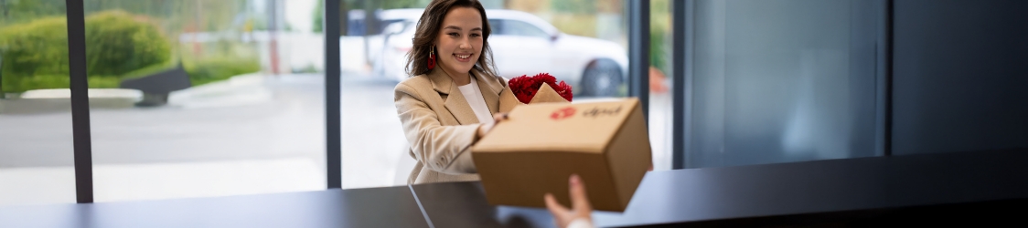 Klient odbiera przesyłkę od pracownika w punkcie DPD Pickup przy ladzie sklepu