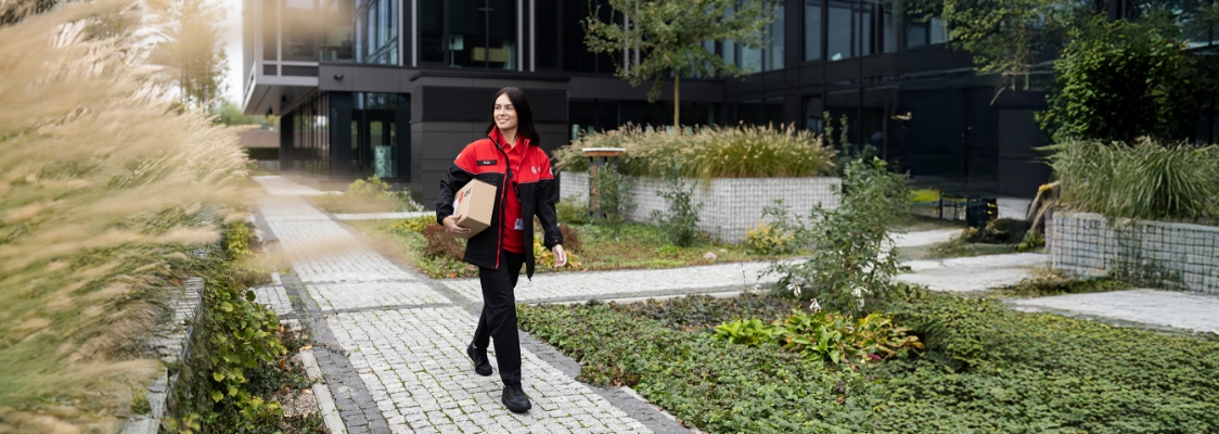 Kurier DPD wręcza paczkę uśmiechniętemu klientowi przy drzwiach