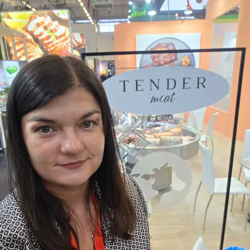 Brunetka na tle szklanej ściany z niebieską naklejką "tender meat"