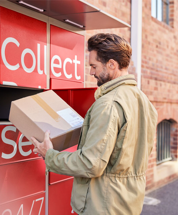 Mann hält ein Paket vor einer Paketstation