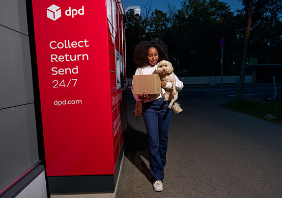 Kundin holt ein Paket mit ihrem Hund an einer DPD-Pickup-Station ab, verfügbar rund um die Uhr.
