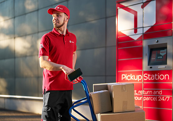 DPD-Mitarbeiter legt ein Paket in eine Pickup Station zur Abholung durch den Kunden.