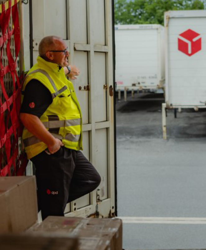 Lagerarbeiter steht in einem geöffneten LKW zwischen Paketen