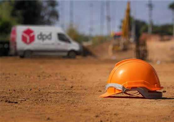 Baustelle mit DPD Sprinter im Hintergrund und Bauhelm im Vordergrund.