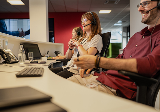 Mitarbeiter arbeiten im Kundenservice und lachen gemeinsam.